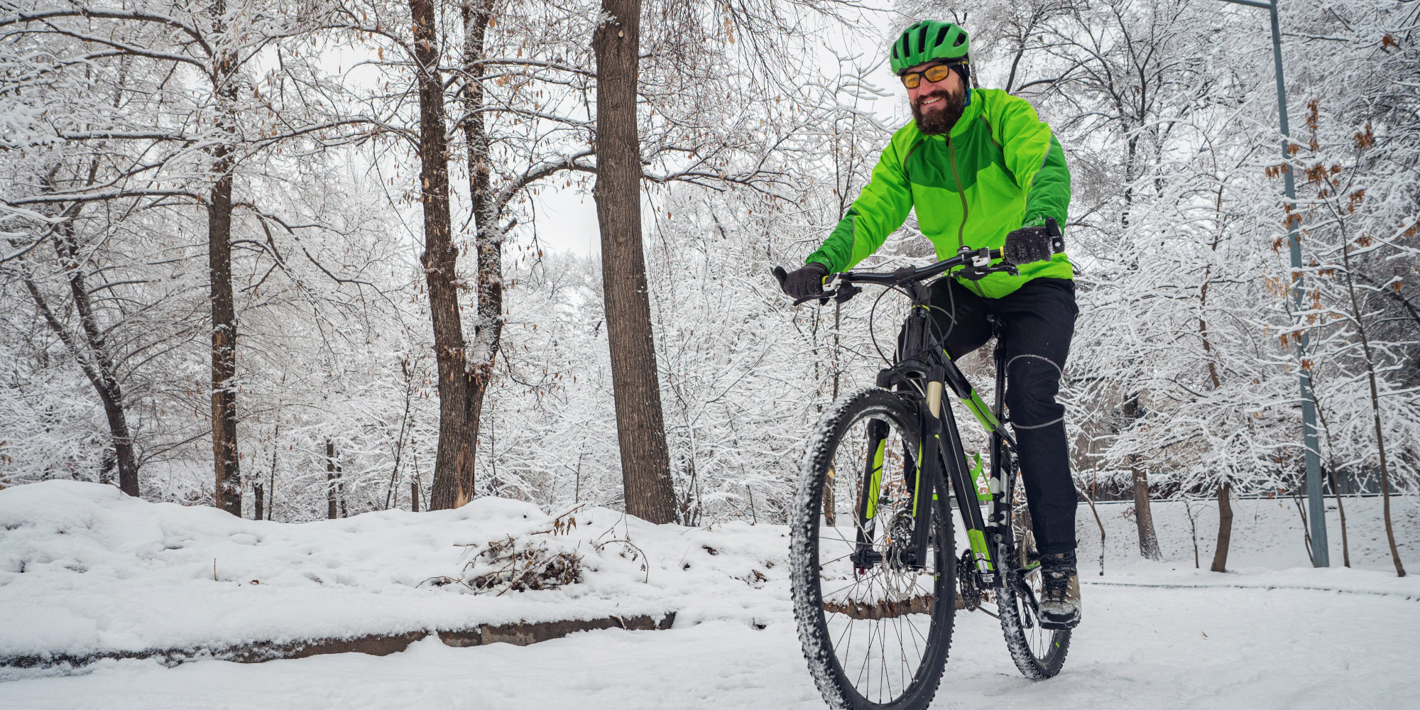 Spaß beim Radfahren im Winter mit der richtigen Bekleidung Mann fährt mit einem Fahrrad durch eine Schneebedeckte Gegend mit in Winterbekleidung.