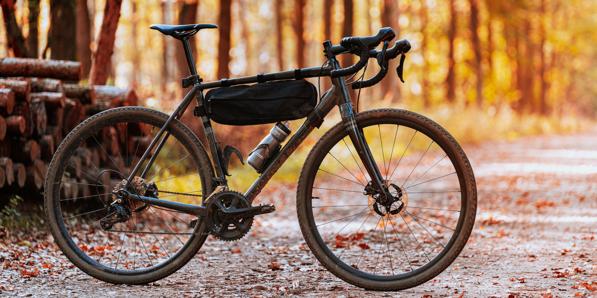 Schwarzes Fahrrad auf einem Kiesweg, umgeben von herbstlichen Bäumen.