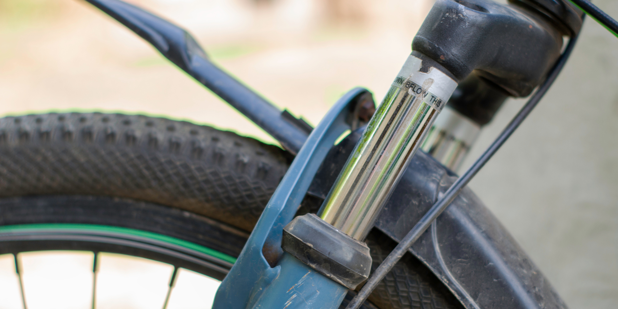 Nahaufnahme eines Fahrradfedergabels mit Gummireifen im Hintergrund.