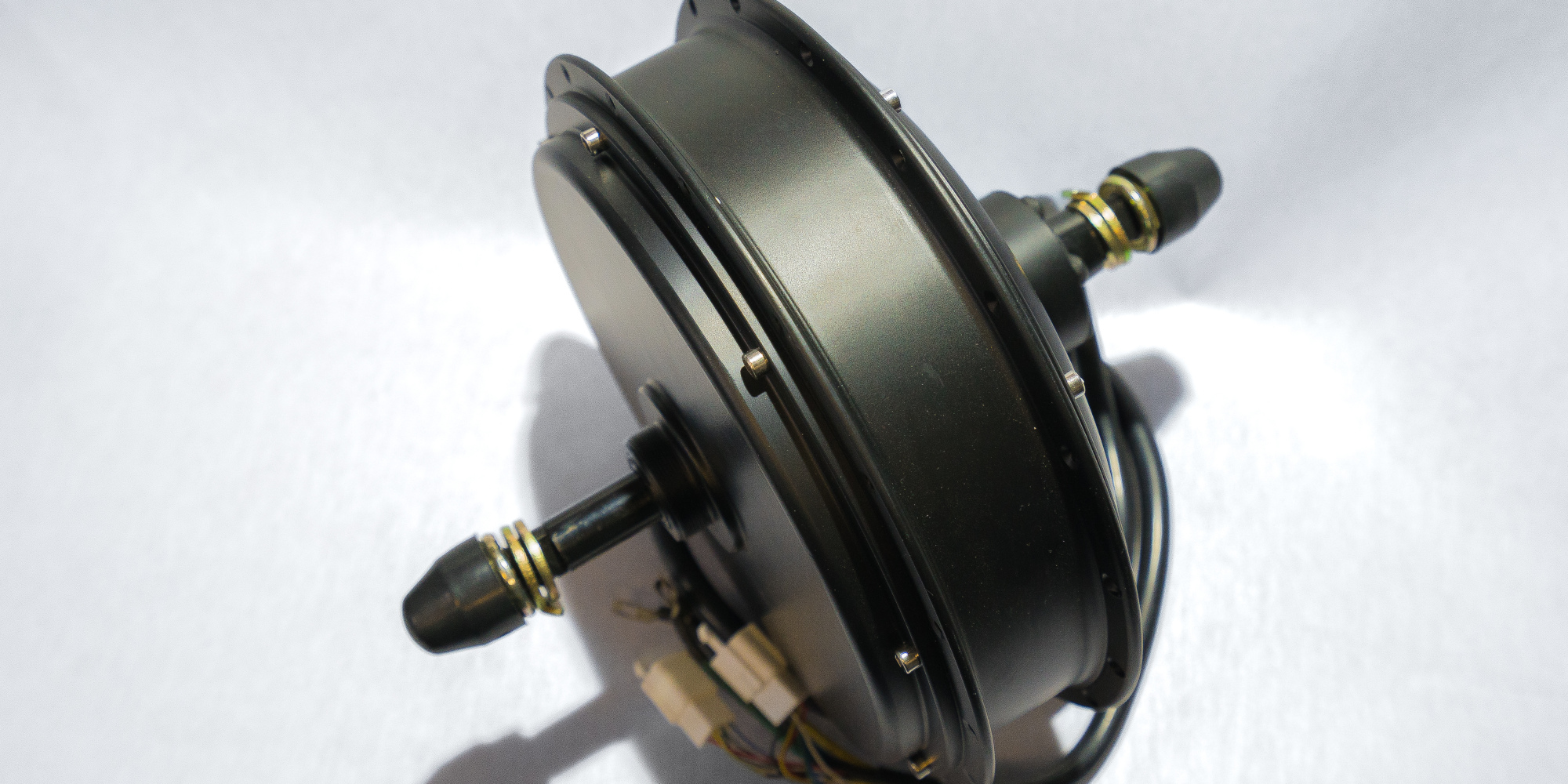 Schwarzer Motor mit zwei Anschlüssen, auf weißem Hintergrund.
