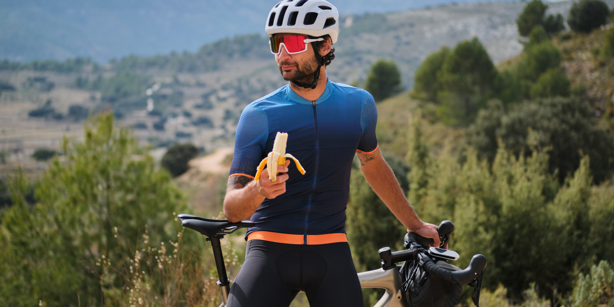 Mann in Radklamotten isst eine Banane