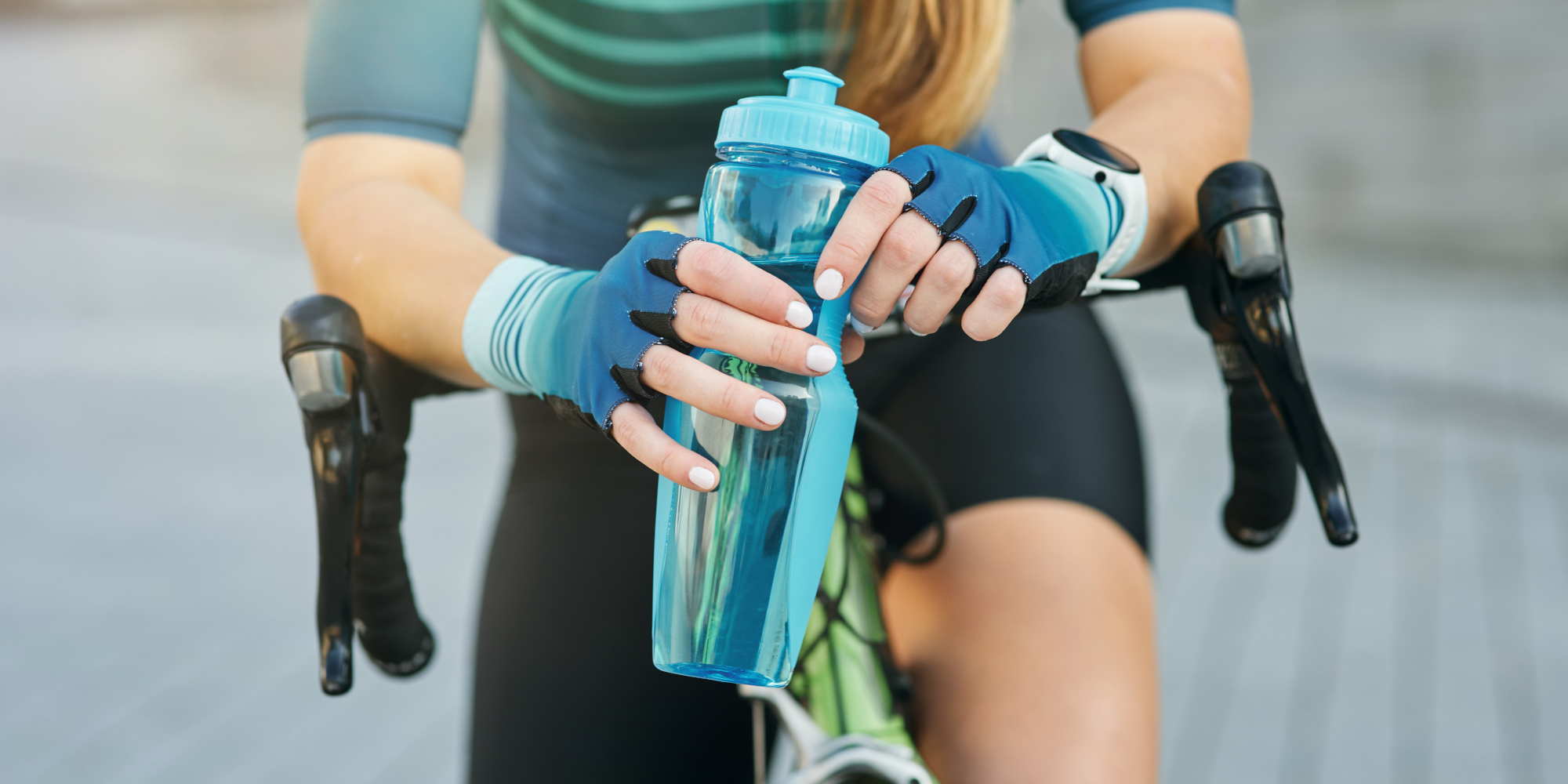 Frau auf einem Fahrrad hält eine Wasserflasche in der Hand