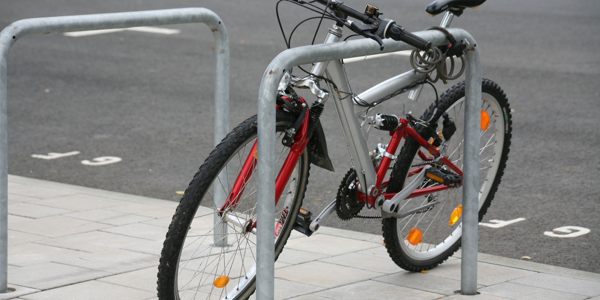 Ein silbernes Mountainbike ist an einem Fahrradständer befestigt.