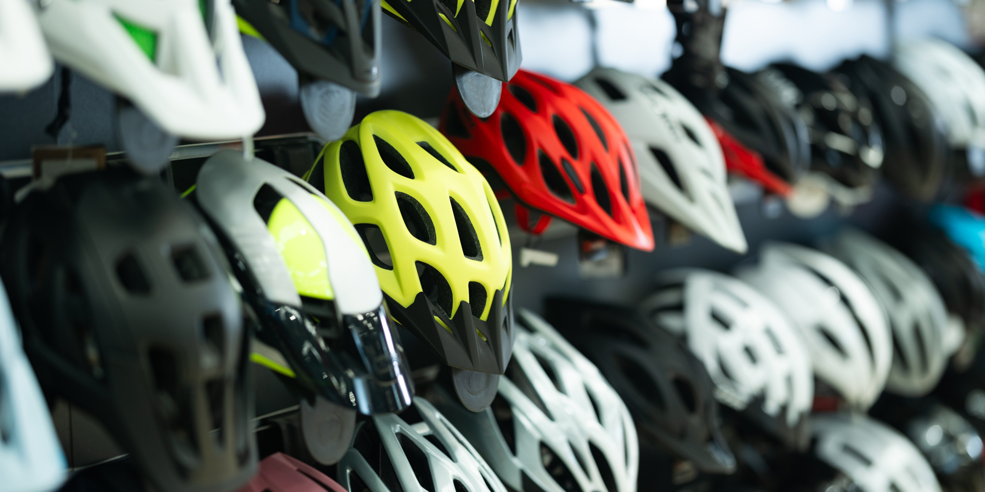 Bunte Fahrradhelme in verschiedenen Größen hängen an einem Regal.