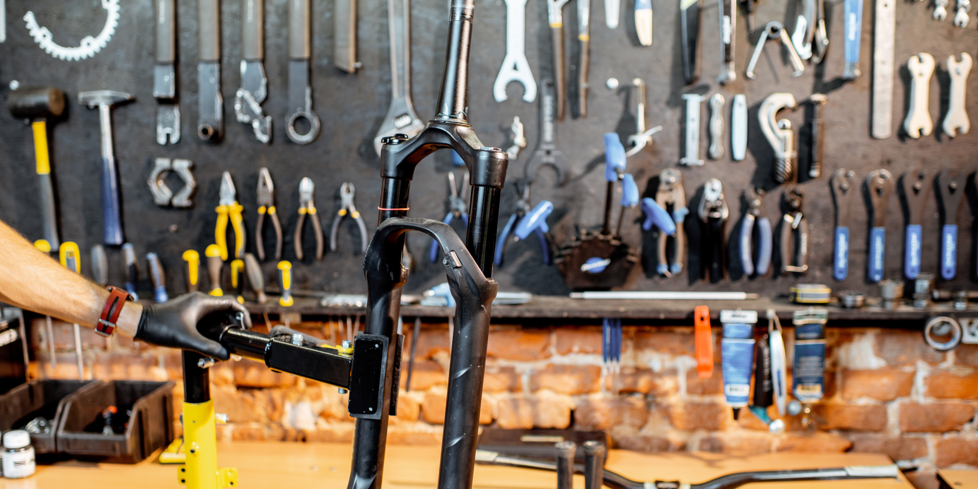 Ein Werkstattbereich mit verschiedenen Werkzeugen an der Wand und einem Bike-Gabel im Vordergrund.