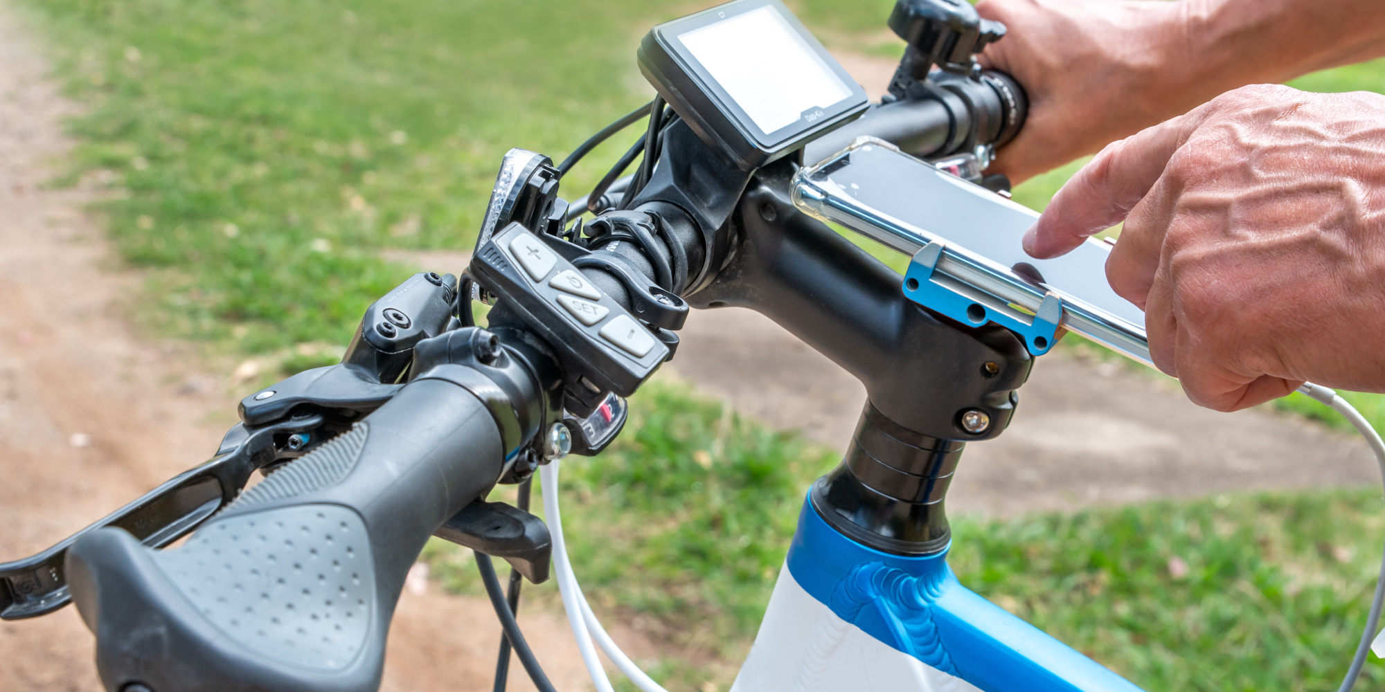 Handy unterwegs ganz einfach aufladen Mann tippt auf einem Smartphone, dass in einer Fahrradhalterung befestigt ist und aufgeladen wird