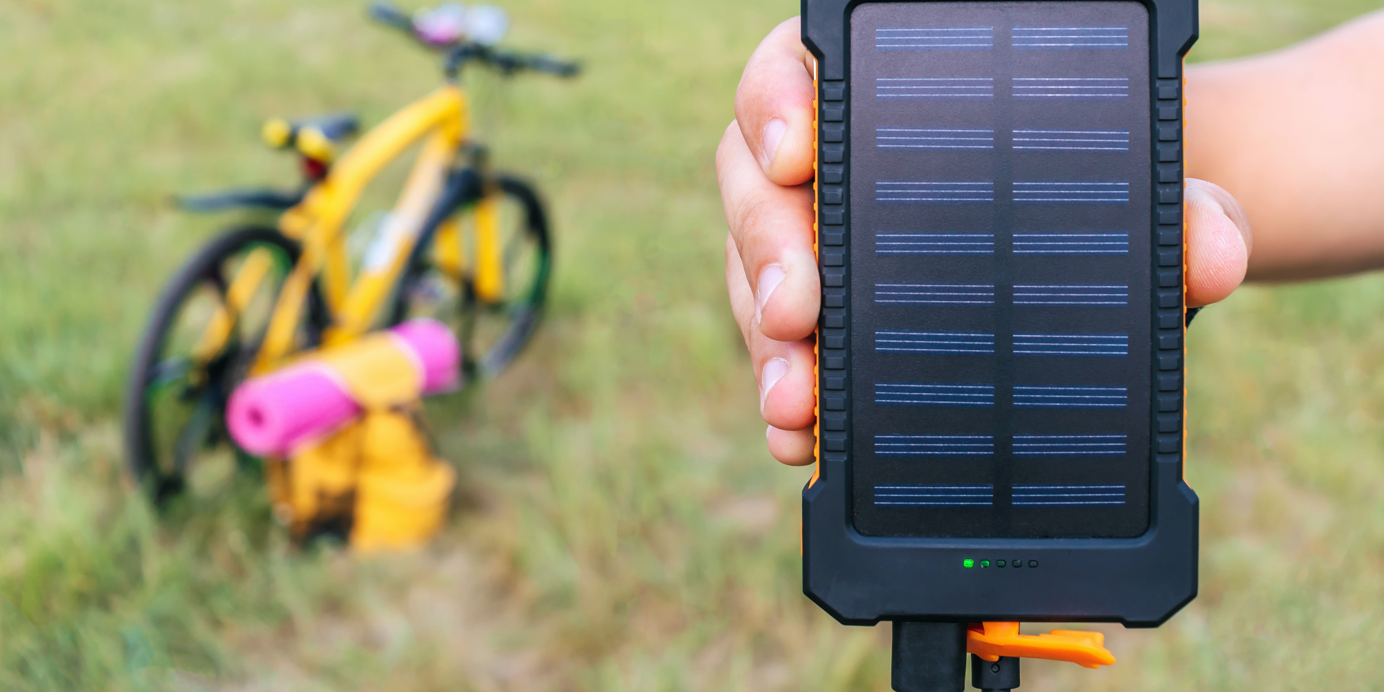 Handy laden mit Sonnenenergie Powerbank mit Solarpanel vor einem Fahrrad