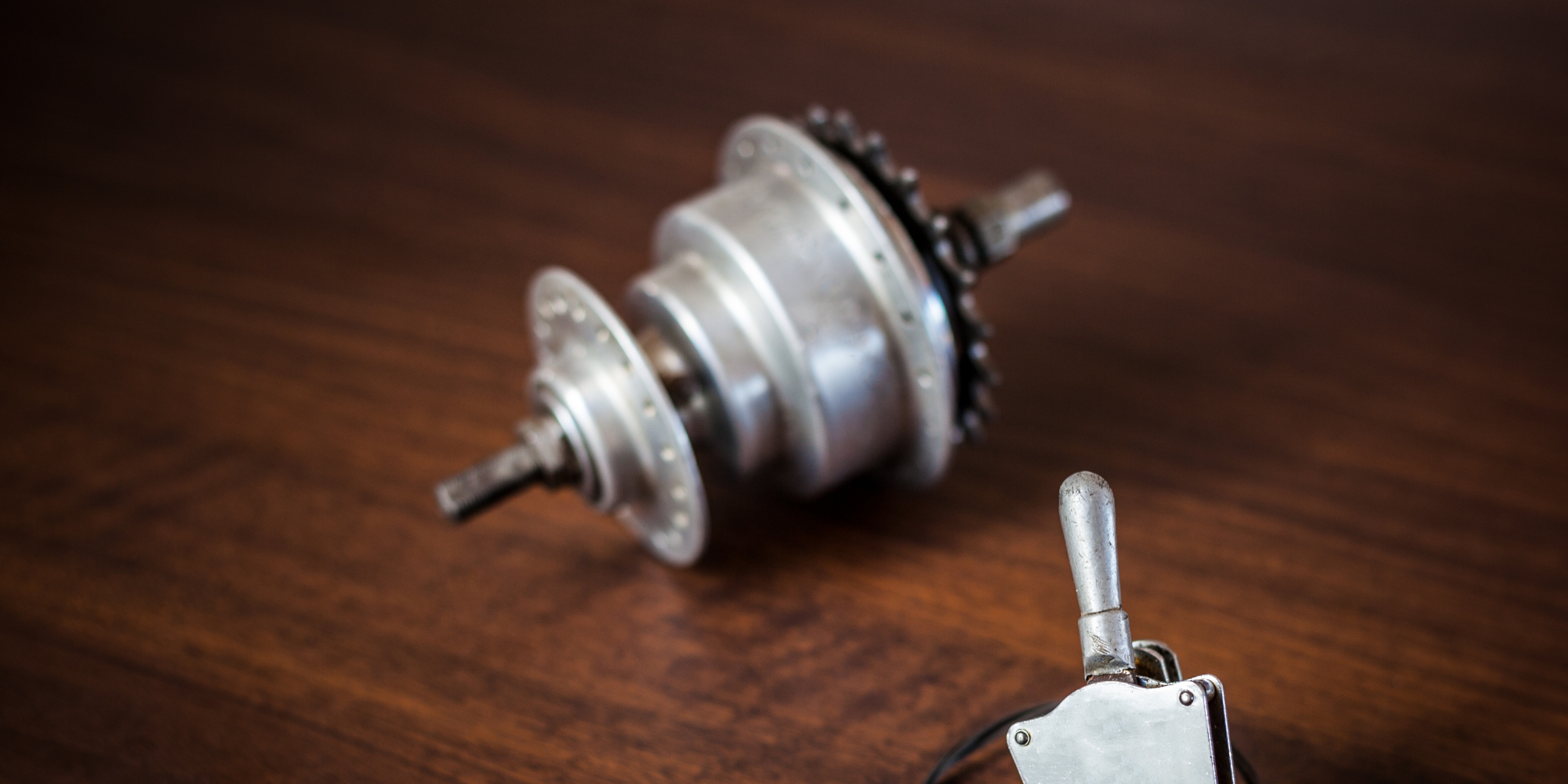 Metallisches Fahrradgetriebe mit Schaltmechanismus auf Holzoberfläche.