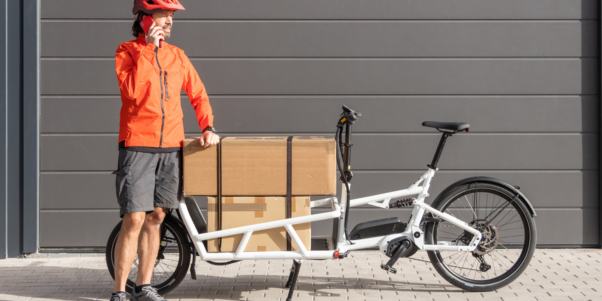 Mann steht neben einem  beladenem Lastenrad