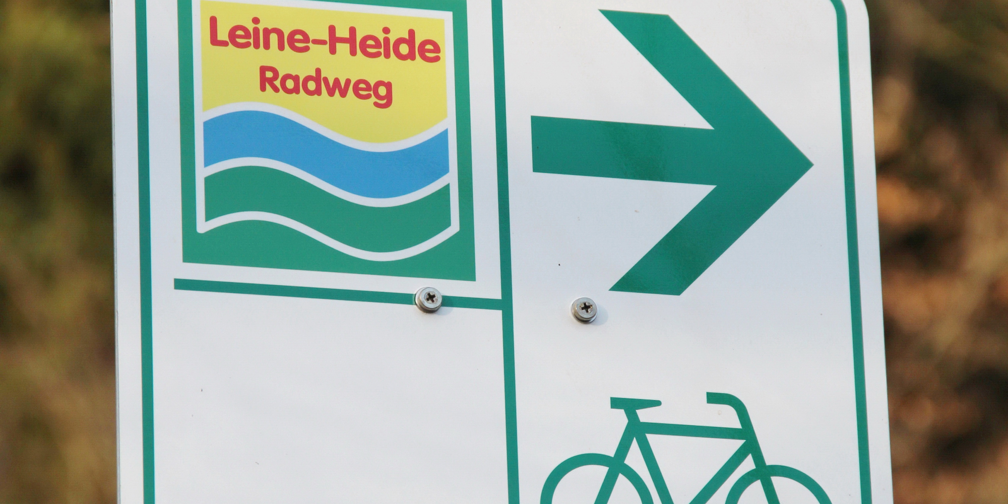 Wegezeichen für den Leine-Heide Radweg mit Richtungspfeil und Fahrradsymbol.