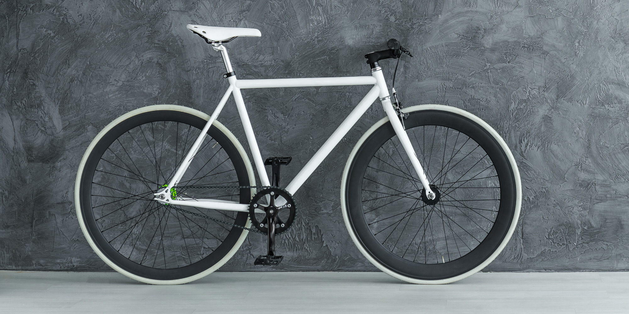 Ein modernes, weißes Fahrrad mit schwarzen Reifen vor einer grauen Wand.