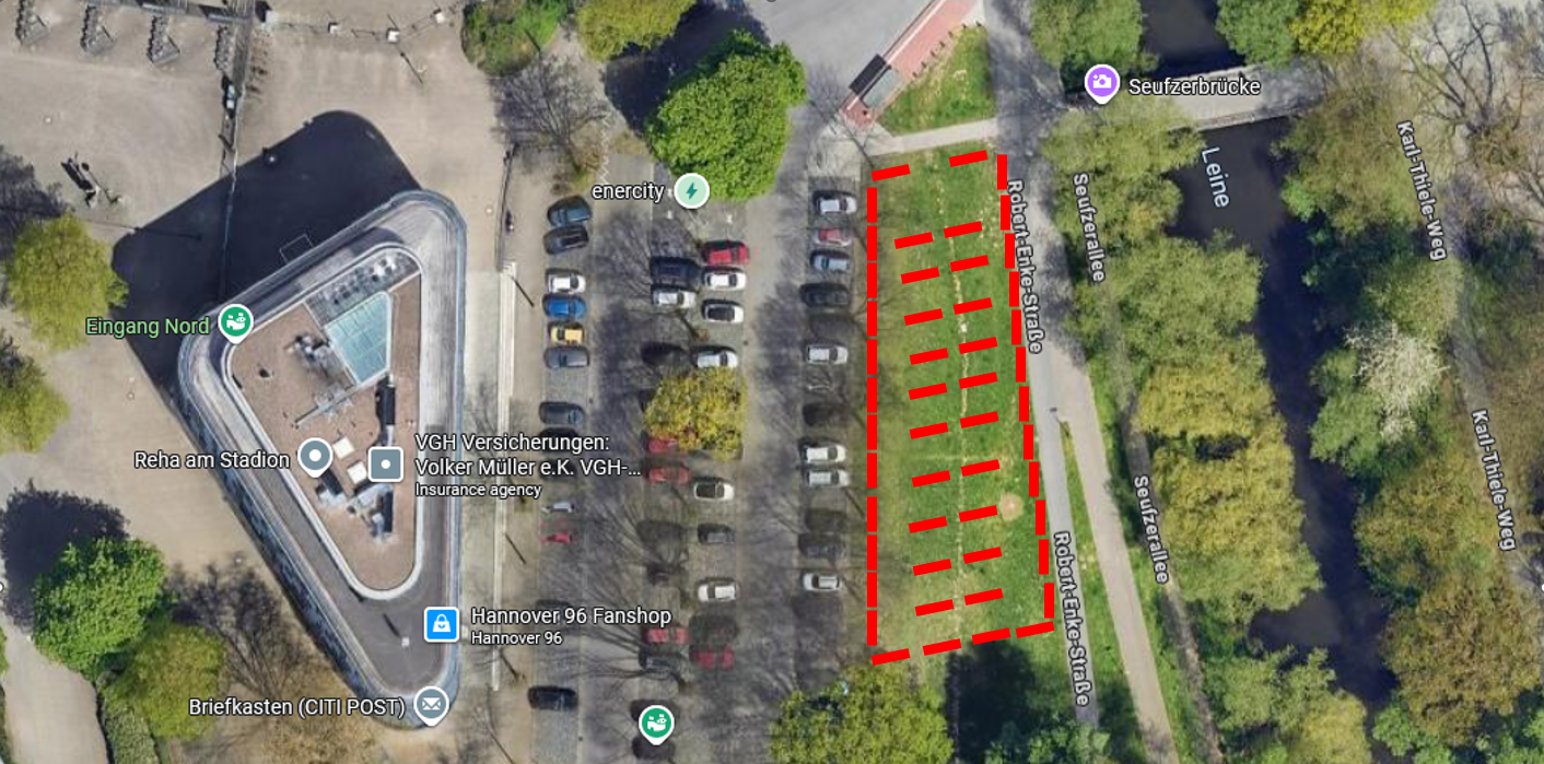 Luftaufnahme eines Parkplatzes neben einem Spielplatz und einem Grünbereich.