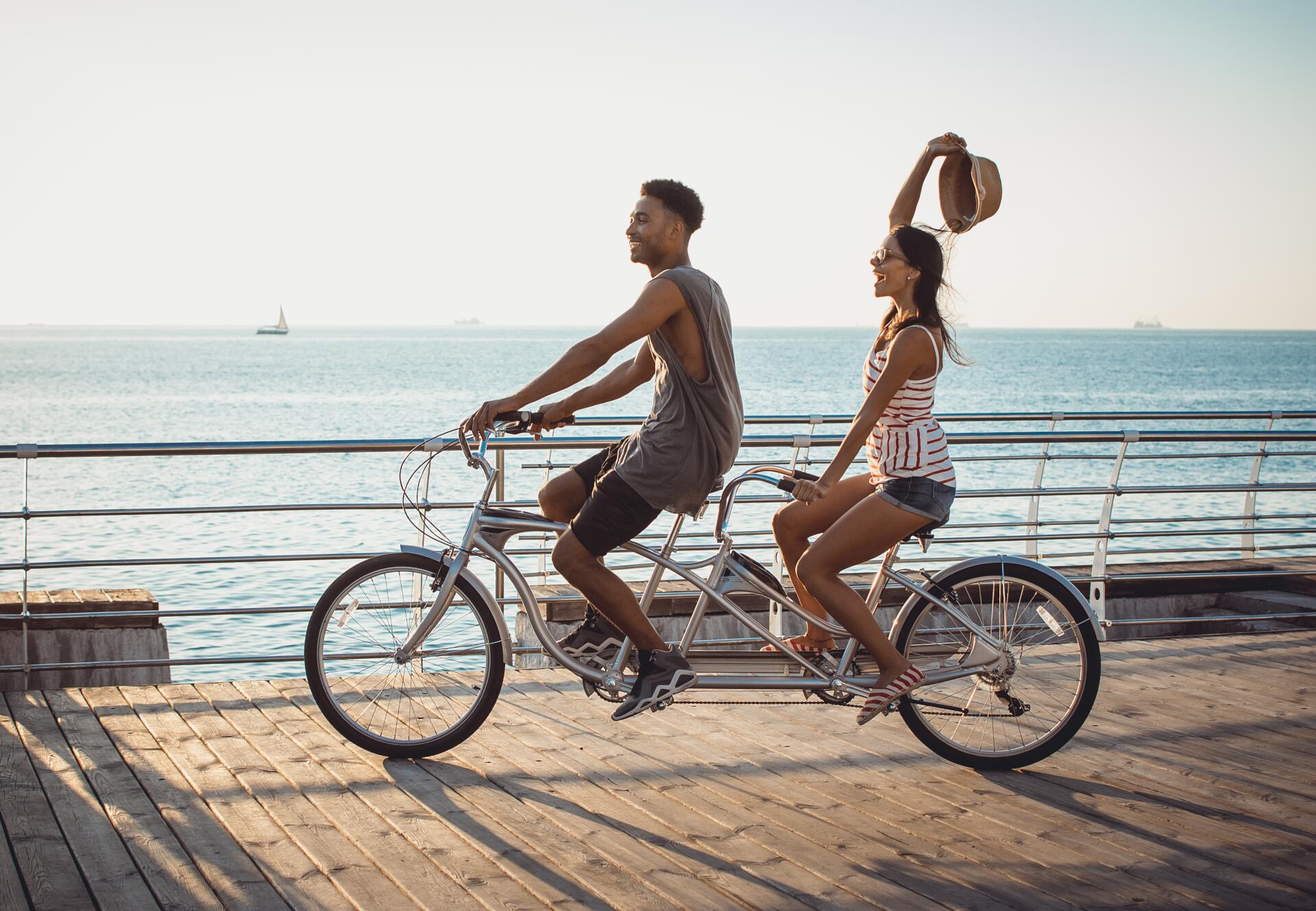 Paar fährt glücklich auf einem Tandemrad am Strand entlang
