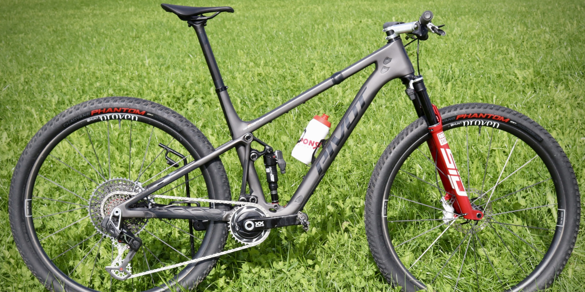 Schwarzes Mountainbike mit roten Akzenten auf einer grünen Wiese.