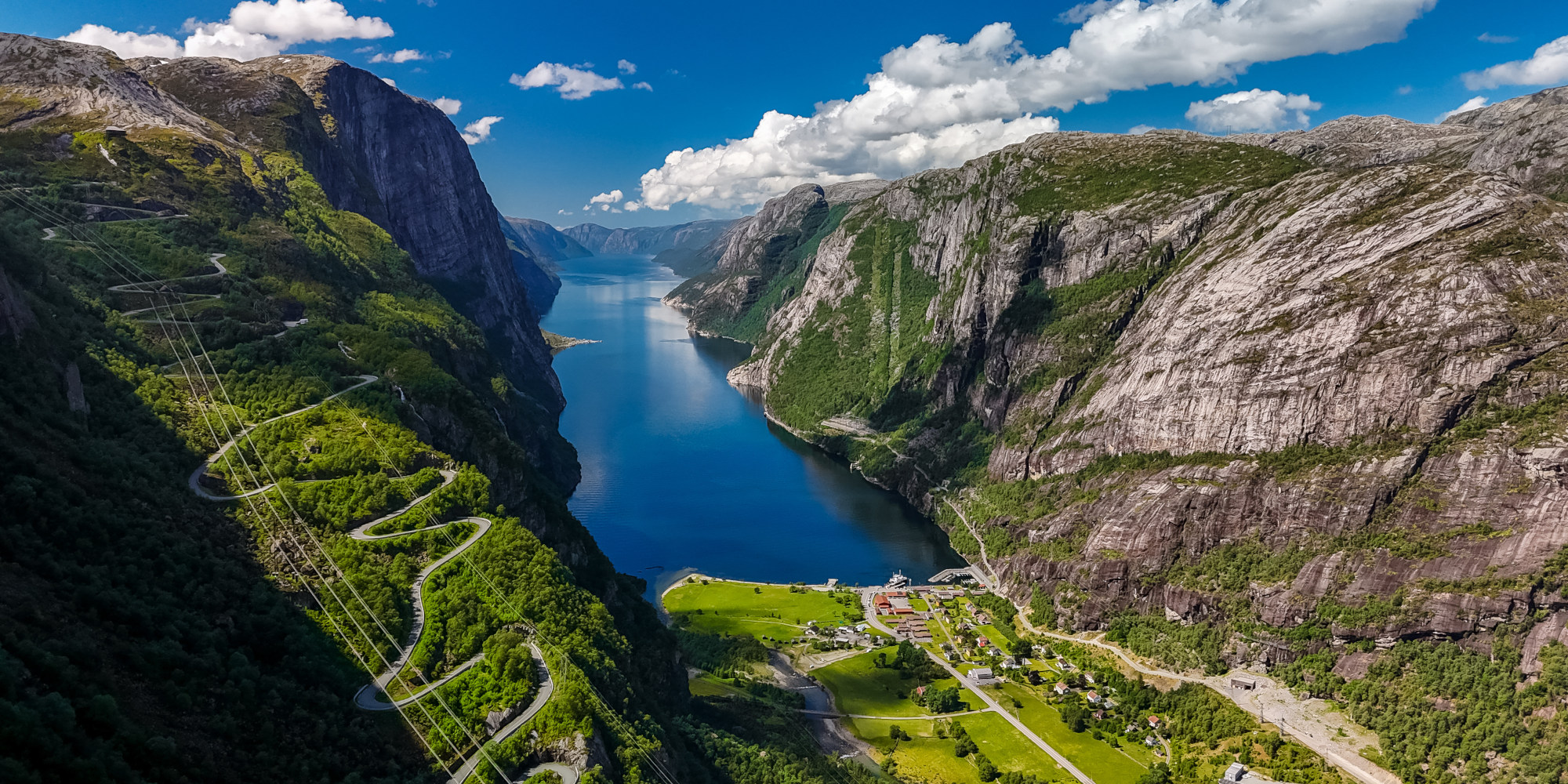 Blick auf einen Fjord umgeben von hohen Bergen und üppiger Vegetation.