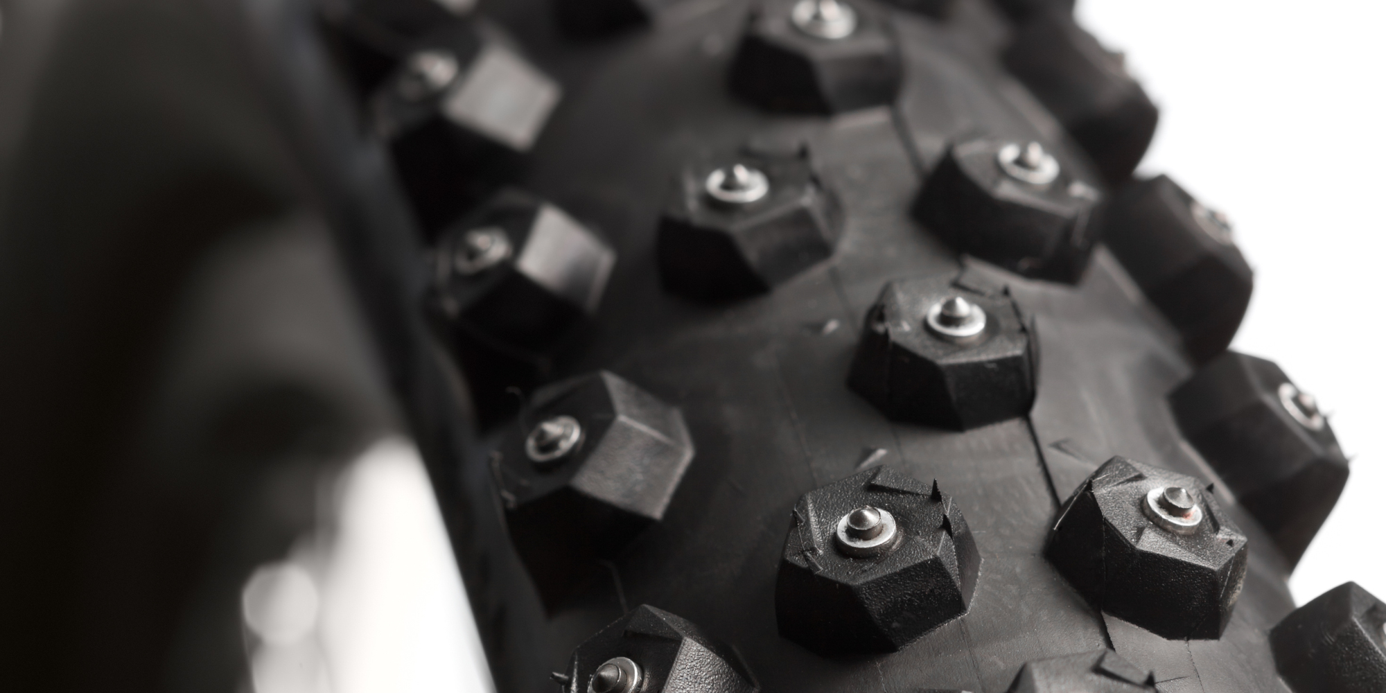 Nahaufnahme eines Mountainbike-Reifens mit grobem Profil und Metallstollen.