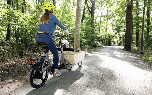 Frau auf einem Lastenrad im Wald