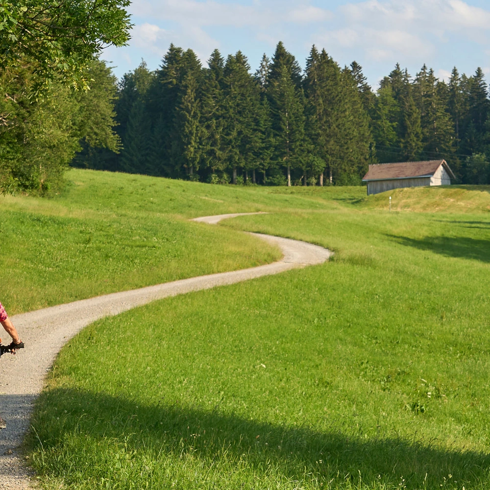 Eine Frau fährt mit einem E-Bike einen langen Weg in der Natur entlang