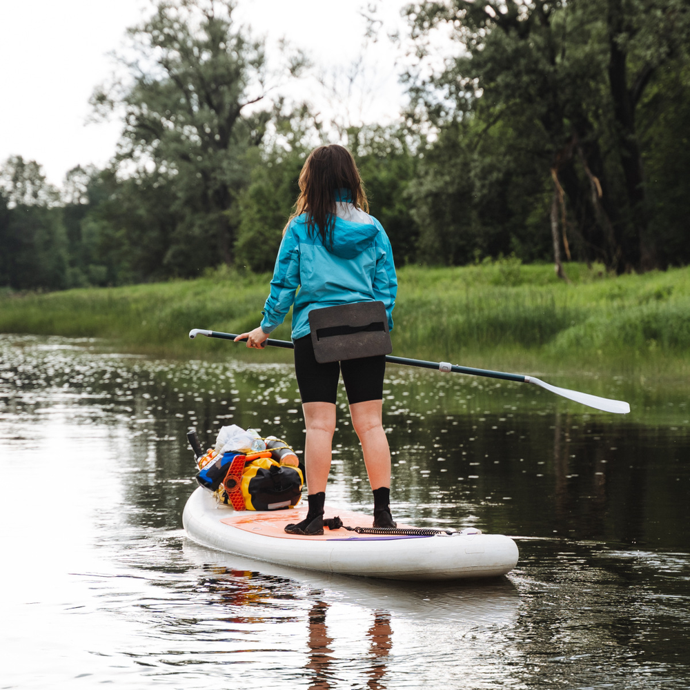 SUP ganz einfach mit dem Fahrrad transportieren Frau fährt mit einem Stand Up Paddle auf einem Fluss