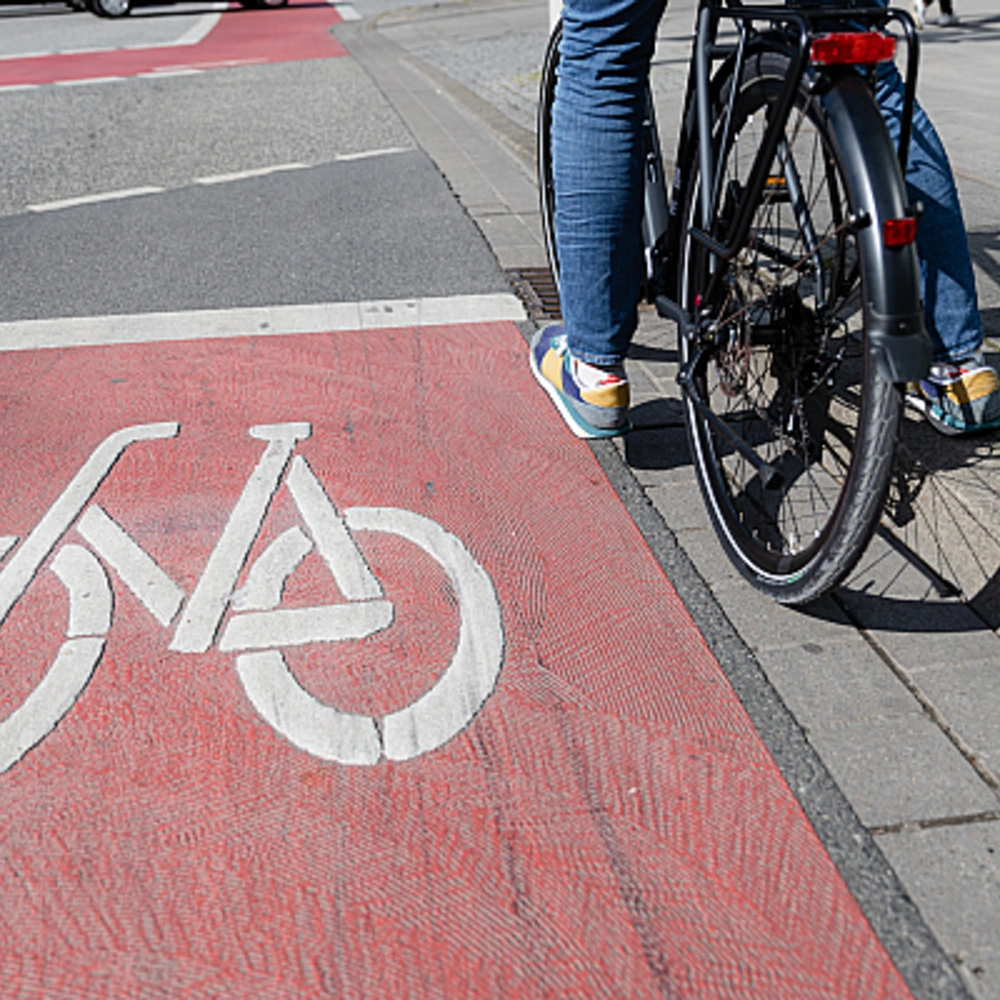 Radfahrer steht auf einem roten Fahrradweg mit einem weißen Fahrradsymbol