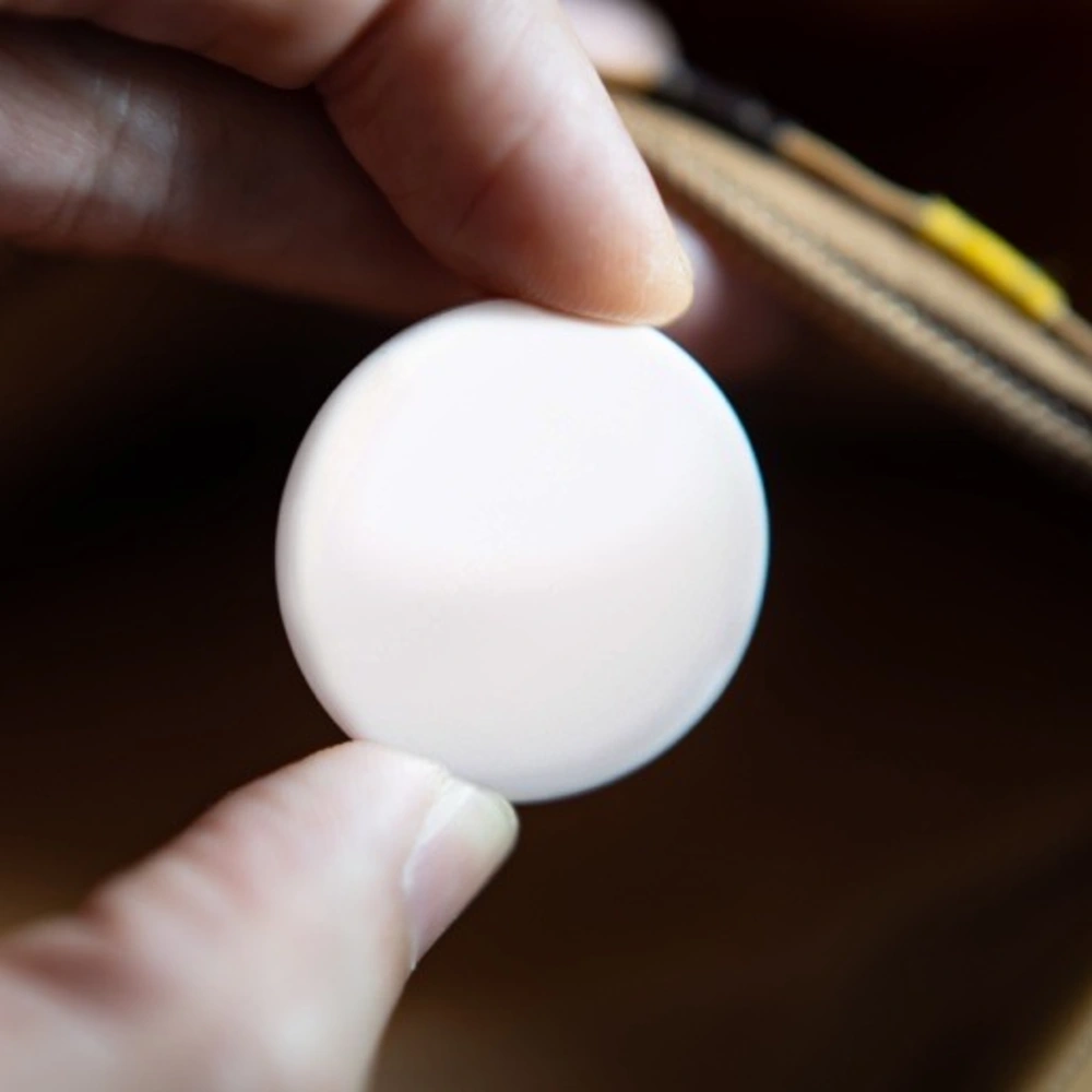 Hand hält einen AirTag über einem offenen Geldbeutel.