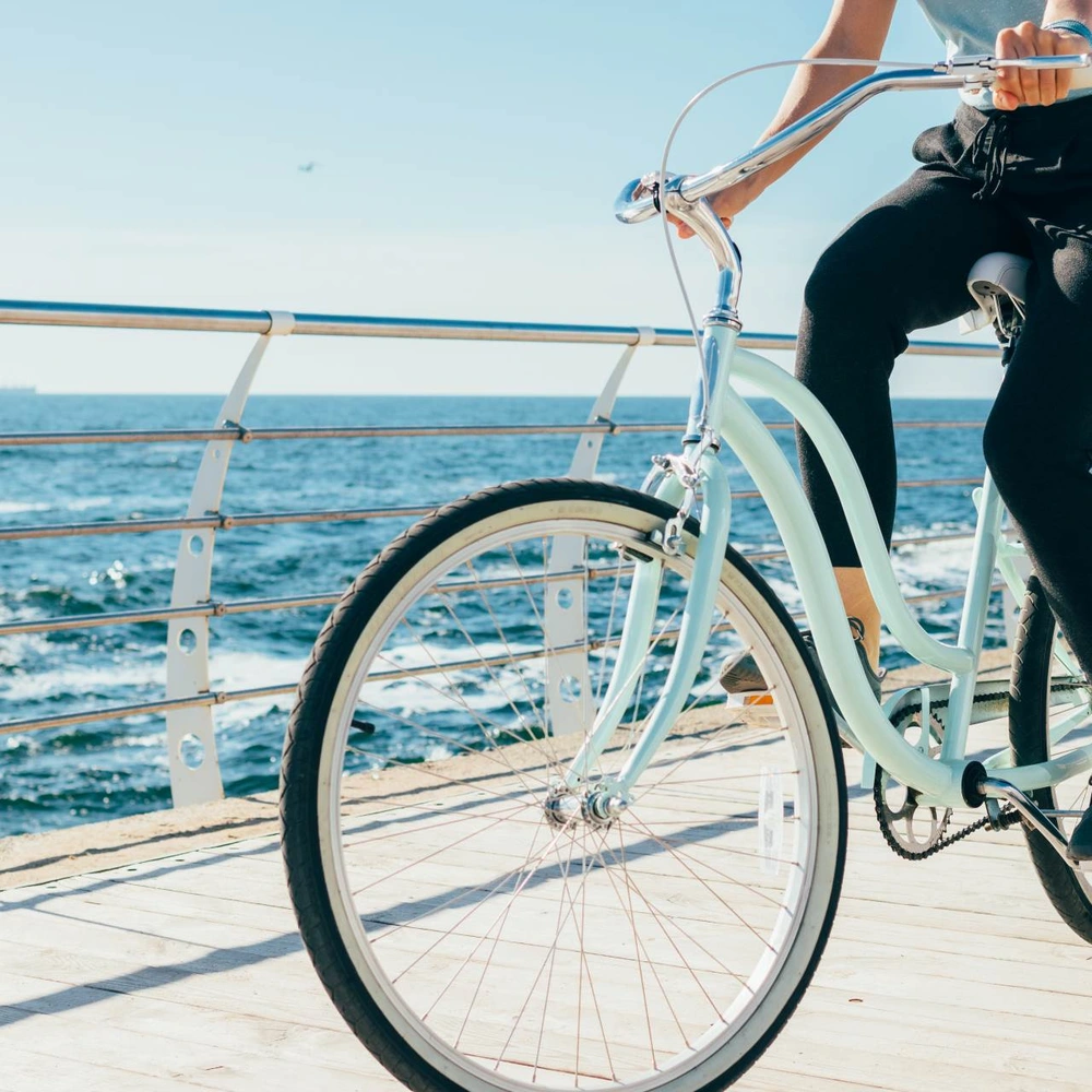 Frau auf Fahrrad in Vintage Optik am Meer