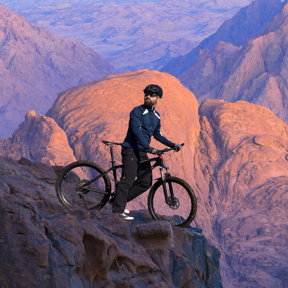 Mann steht mit einem Carbon Bike auf einem Felsen
