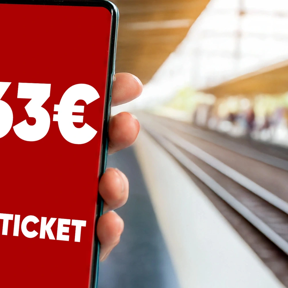 Hand hält ein Smartphone mit einem D-Ticket und Preisangabe am Bahnhof.