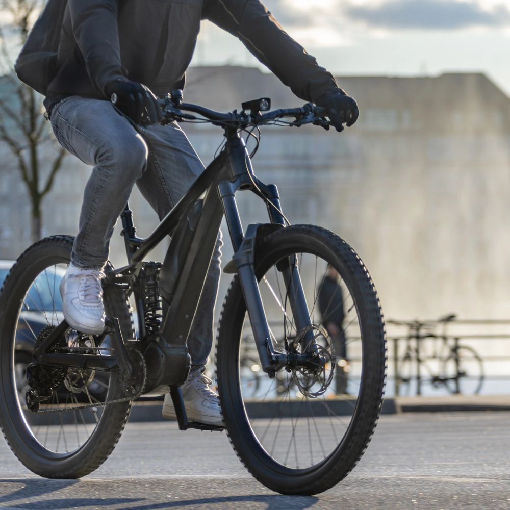 Radfahrer in urbaner Umgebung, vorbei an einem Wasserfall und Fußgängern.
