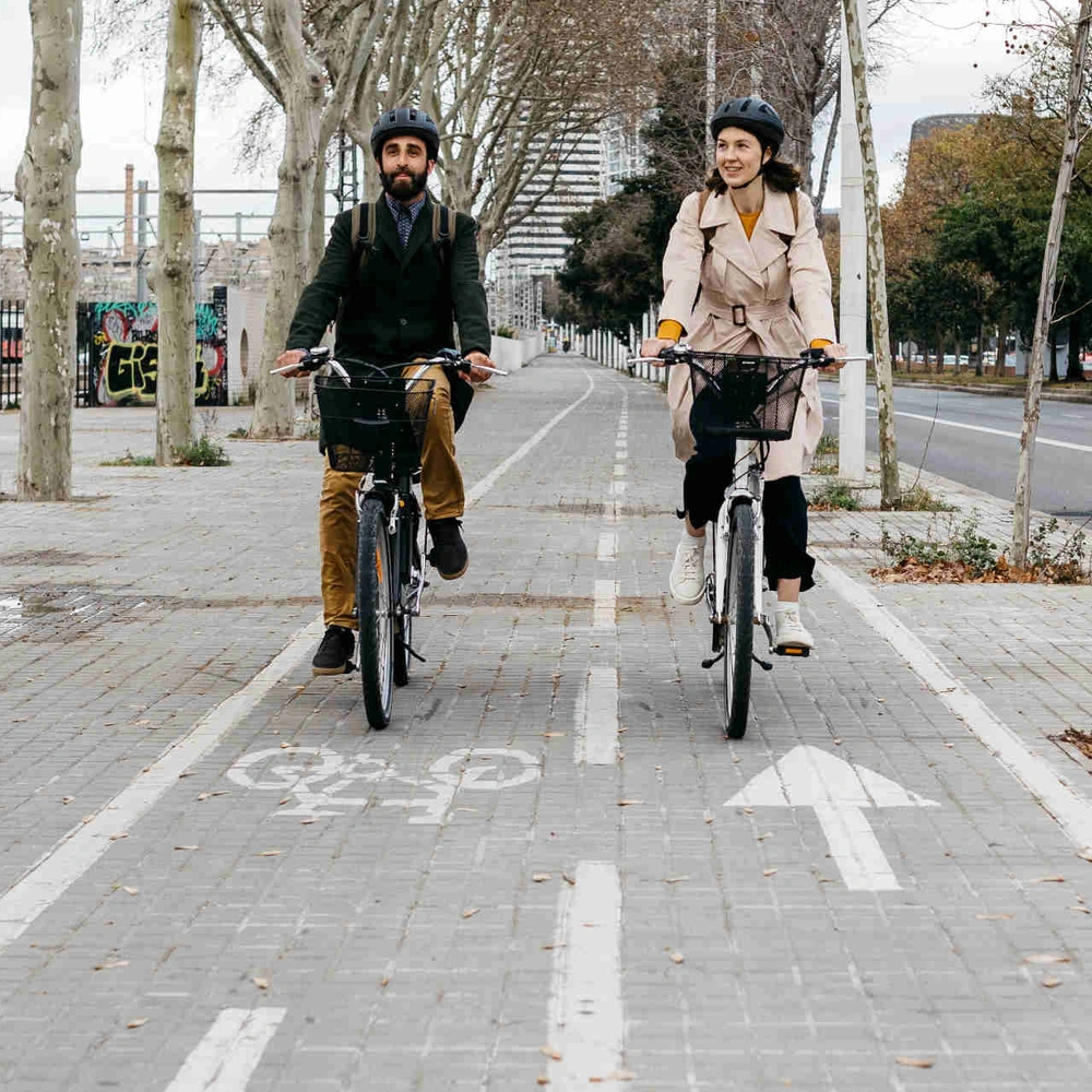 So bist du auf deinem E-Bike sicher unterwegs. Zwei Personen fahren nebeneinander auf Fahrrädern über einen Radweg.