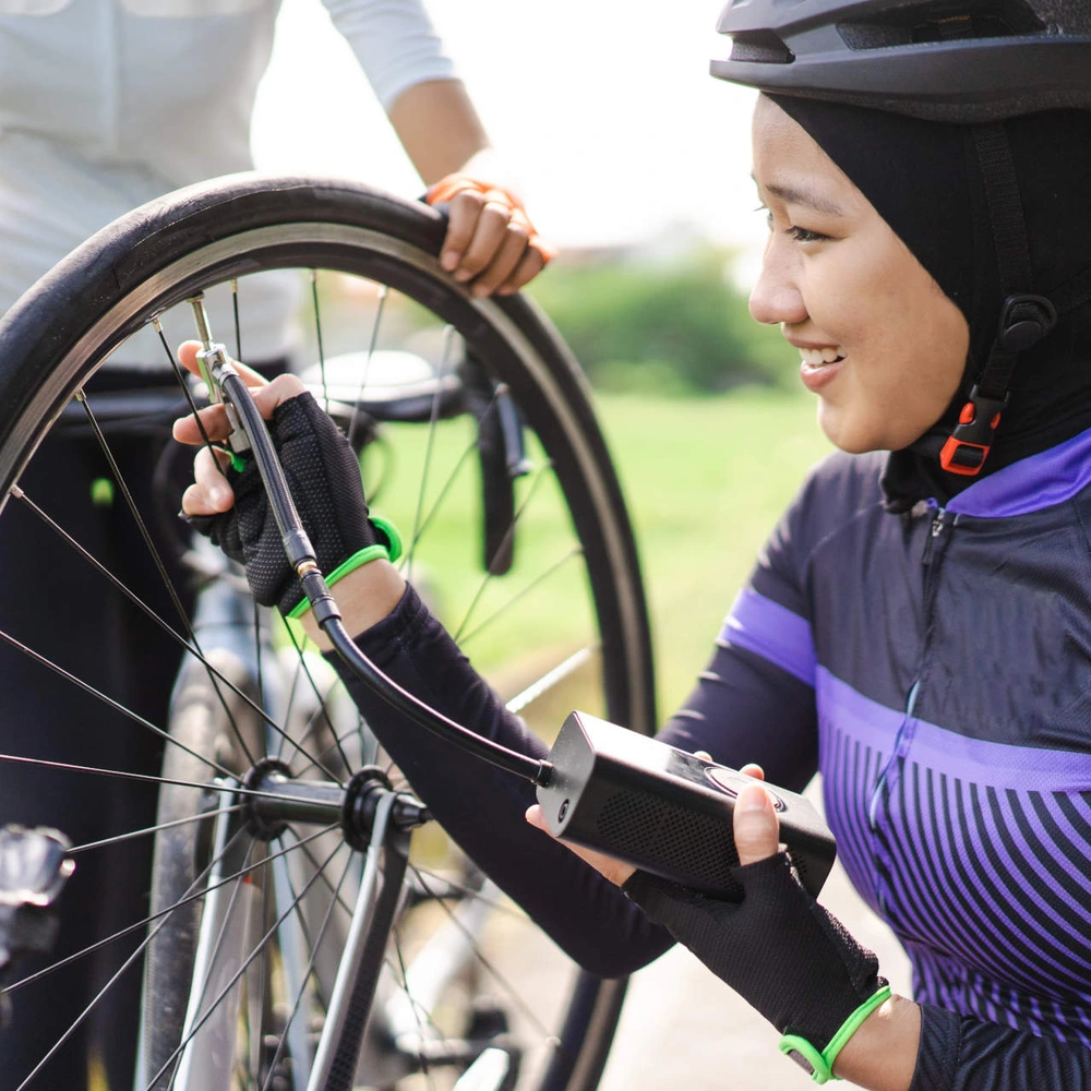 Frau pumpt das Fahrrad mit einer elektrischen Fahrradpumpe auf