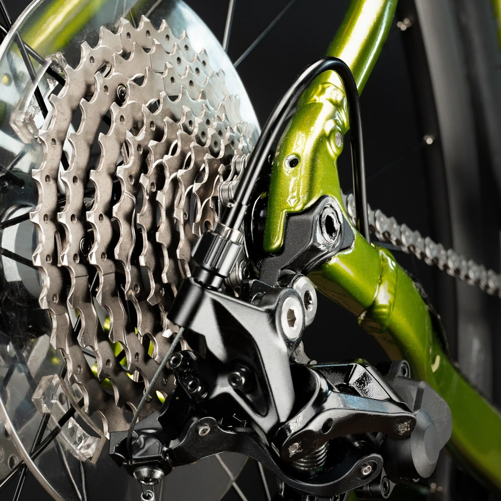 Detailansicht eines Fahrradschaltwerks mit grünem Rahmen und Bremsen.