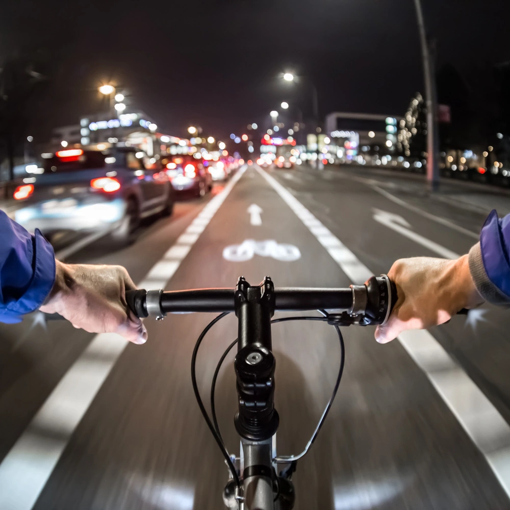 Blick von einem Radfahrer, der nachts auf einer Straße mit Verkehrslichtern fährt