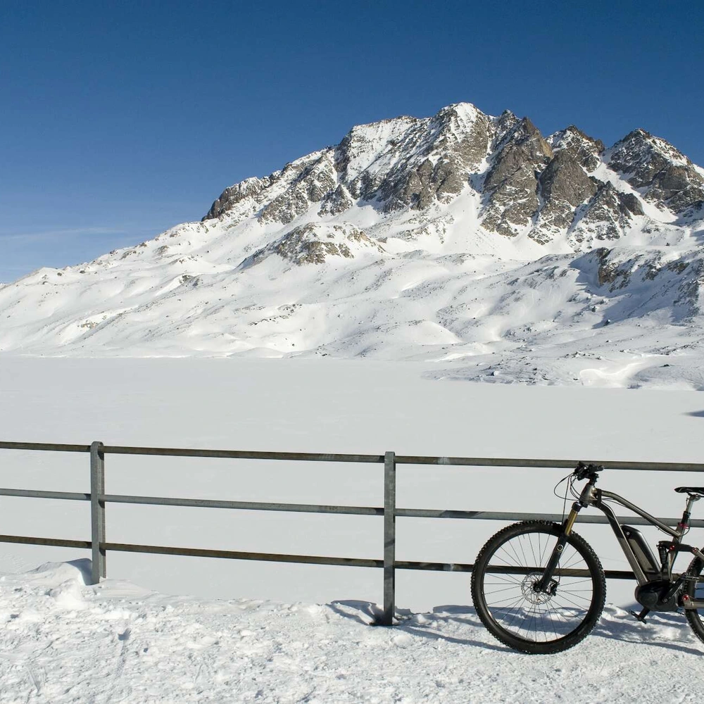 Fahrrad lehnt an inem Zaun vor wuinterlicher Bergkulisse