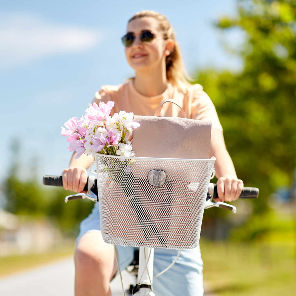 Fahrradkorb befestigen leicht gemacht! Frau fährt auf Rad mit Fahrradkorb durch eine sonnige Landschaft