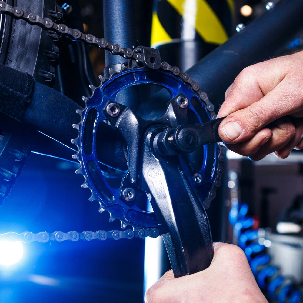 Männerhände schrauben an der Fahrradkurbel in einer Werkstatt