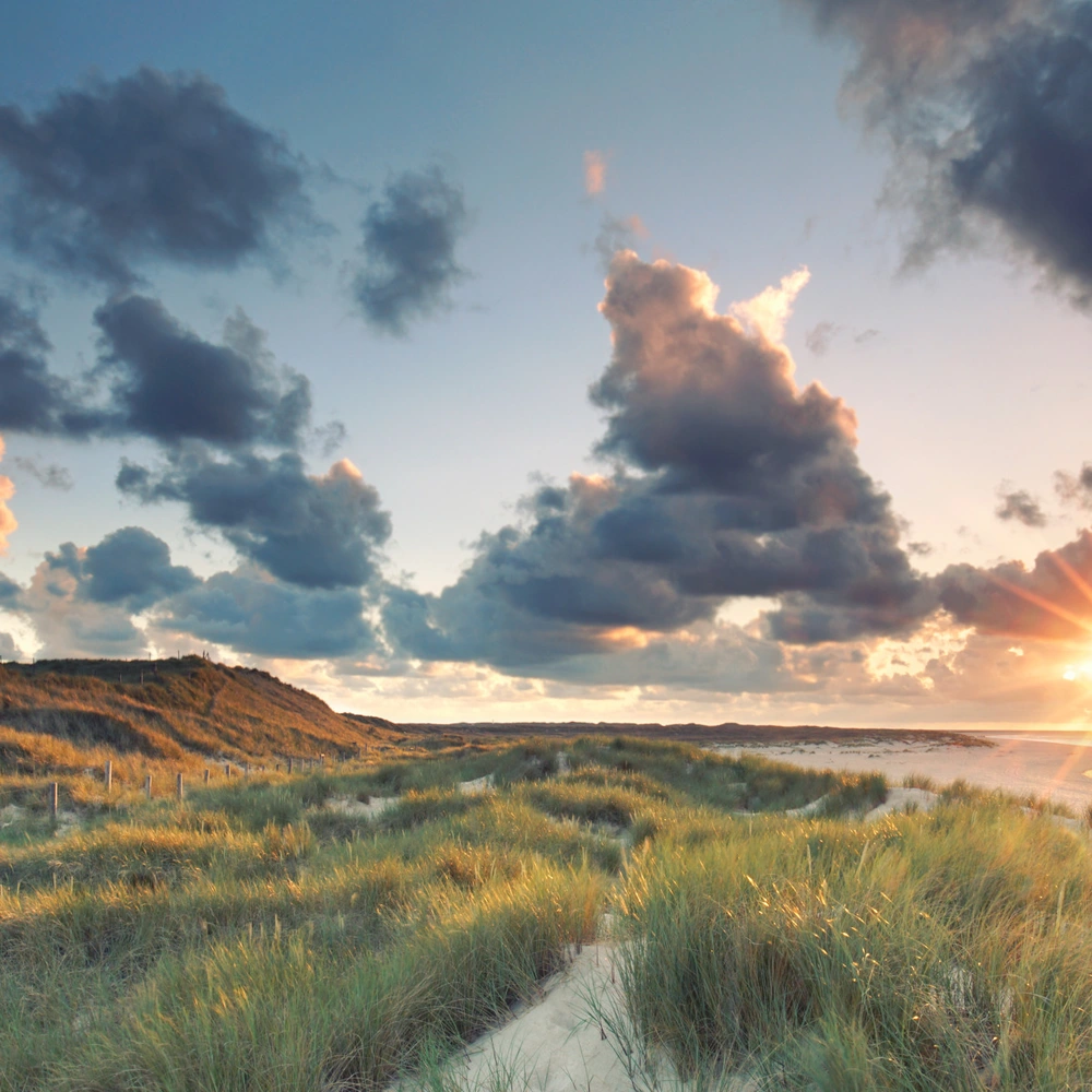 Sonnenuntergang auf der Insel Sylt mit Meer, Dünen und Leuchtturm
