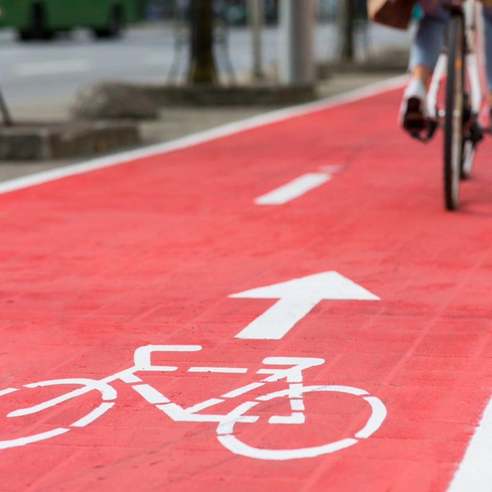 Radweg auf rotem Belag mit weißem Fahrradsymbol und Richtungspfeil