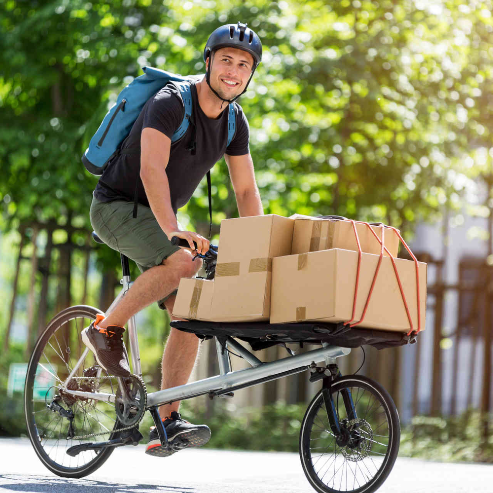 Der große Unterschied bei den Cargo Bikes Man fährt auf Cargo-Bike beladen mit Kartons