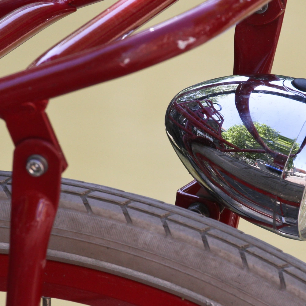 Roten Fahrradlicht mit glänzendem Gehäuse und Reifen im Hintergrund.