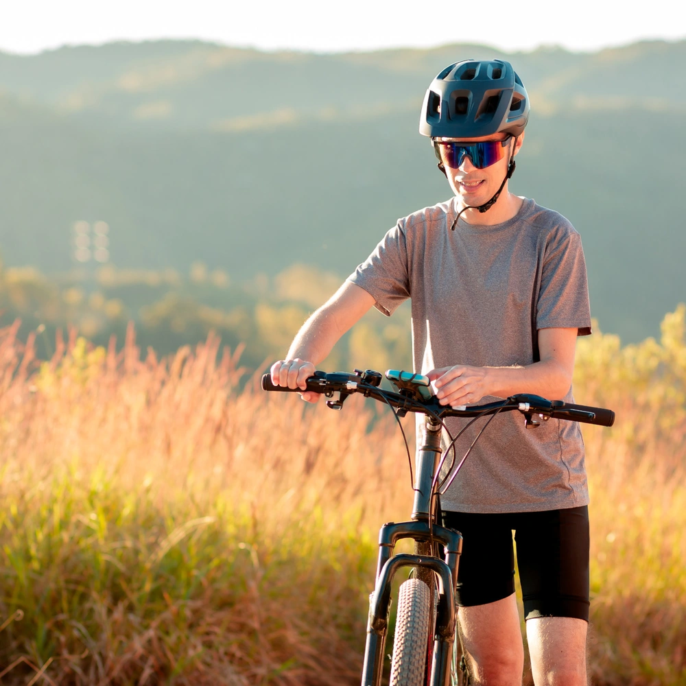 Fahrradfahrer steht mit seinem Fahrrad auf einem Feldweg und klickt auf dem Smartphone
