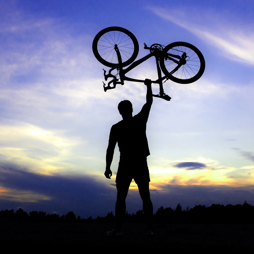 Mann hält ein Mountainbike in den Himmel