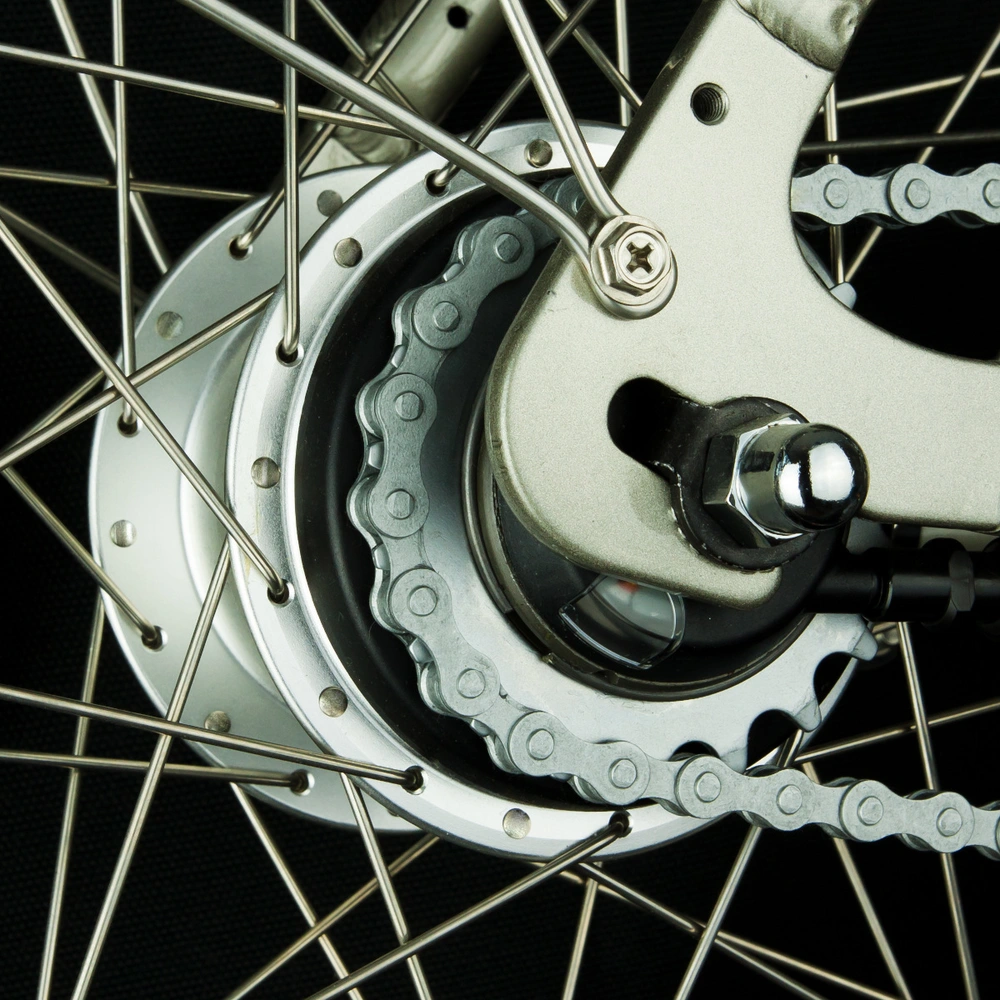 Detailansicht eines Fahrradnaben mit Speichen und Kette auf schwarzem Hintergrund.