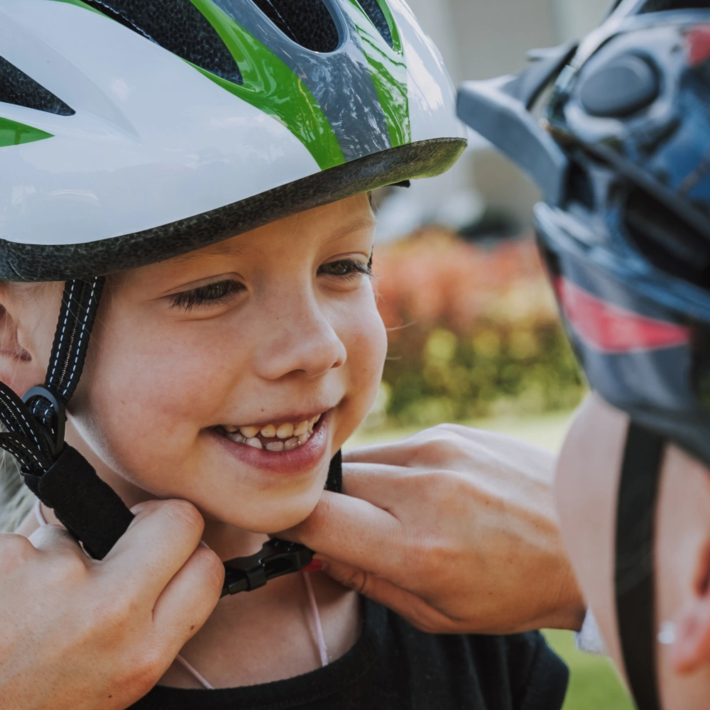 Eine Mutter hilft ihrem Sohn dabei seinen Fahrradhelm zu schließen