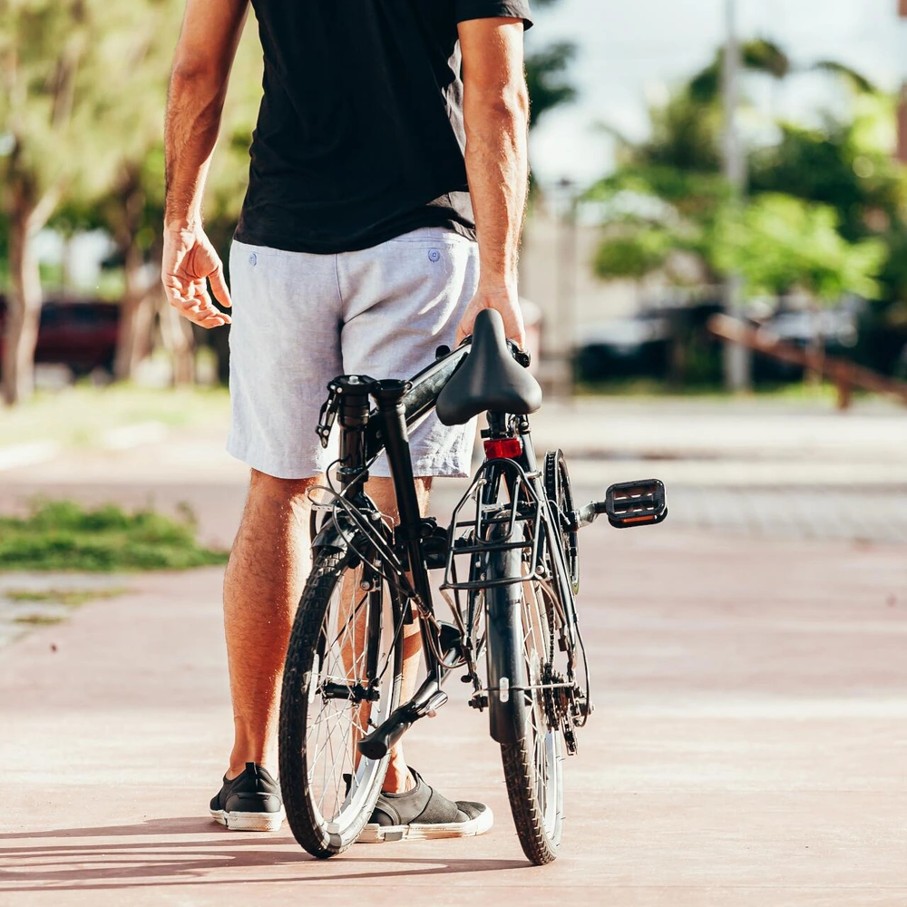 Mann mit seinem Klapprad auf einem gepflasterten Weg in der Nachbarschaft