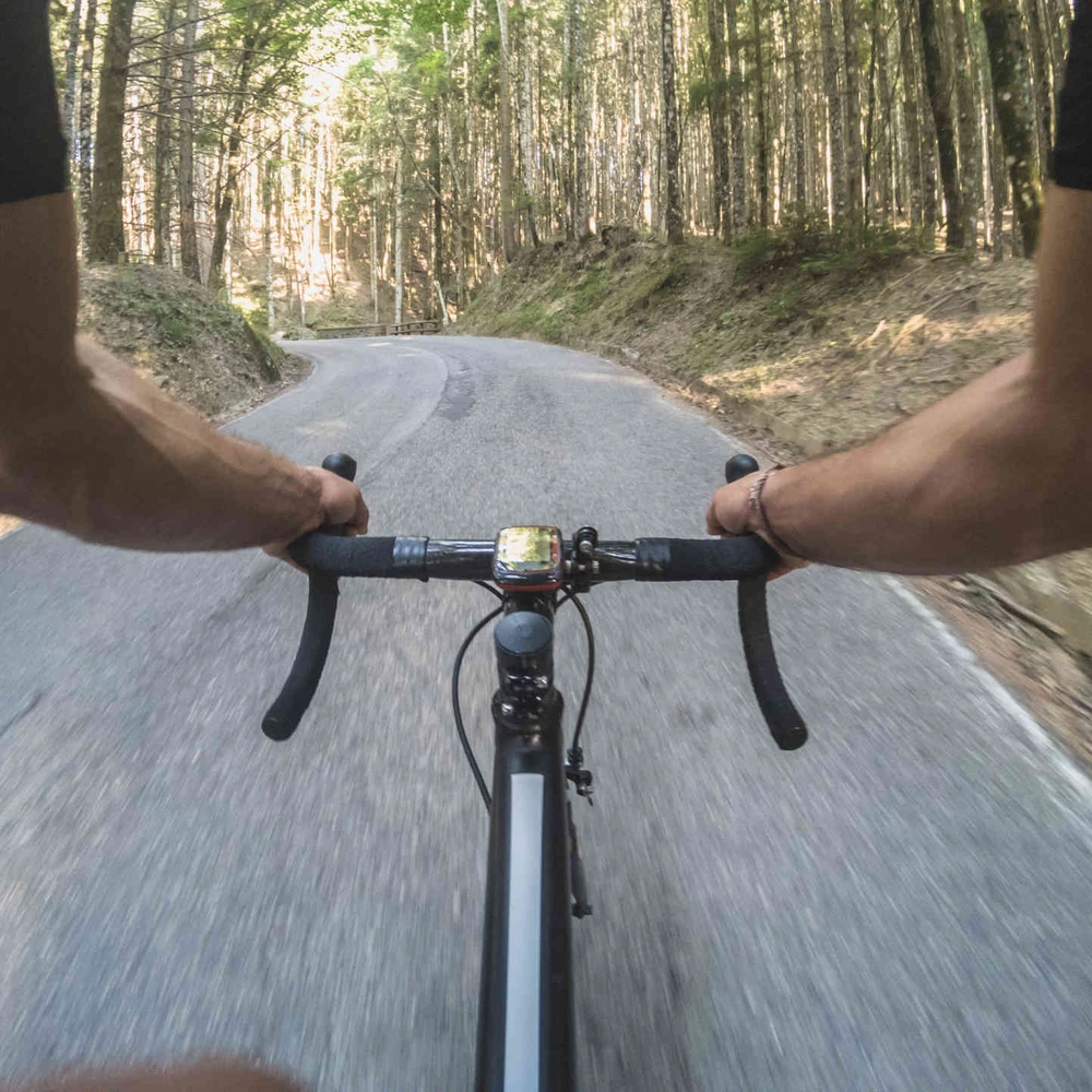 So wickelst du das Lenkerband an deinem Rennrad. Mann auf Rennrad fährt auf Straße durch Wald.
