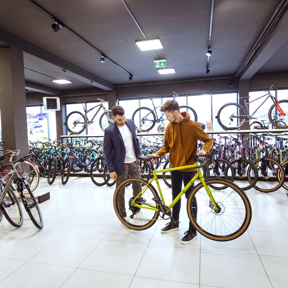 Zwei Männer in einem Fahrradgeschäft, einer hält ein grünes Fahrrad.