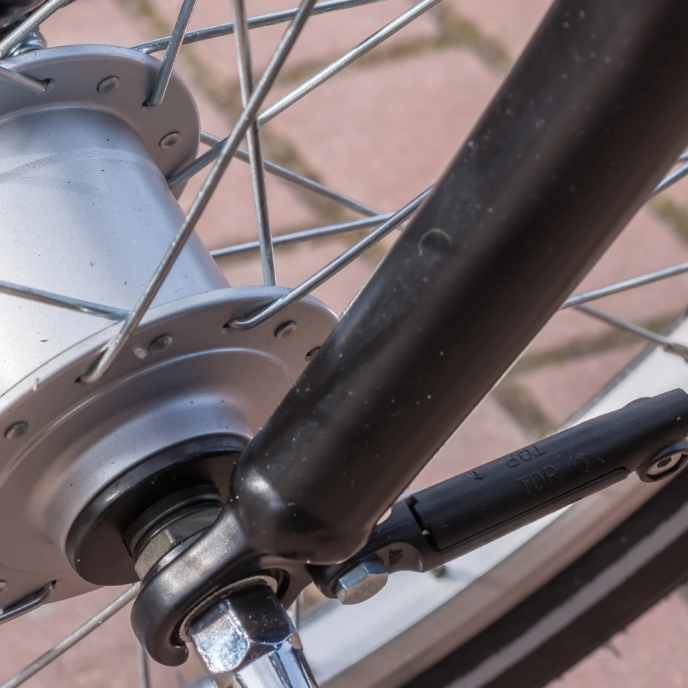 Detailaufnahme eines Fahrradnaben mit Speichen und Gabel auf gepflastertem Boden.