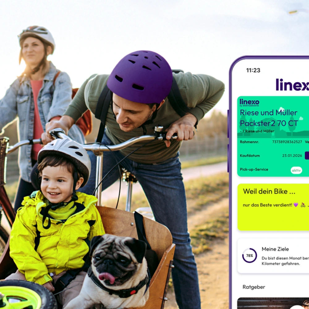 Familie fährt mit Fahrrädern, ein Kind sitzt im Anhänger mit Hund, App auf dem Smartphone sichtbar.
