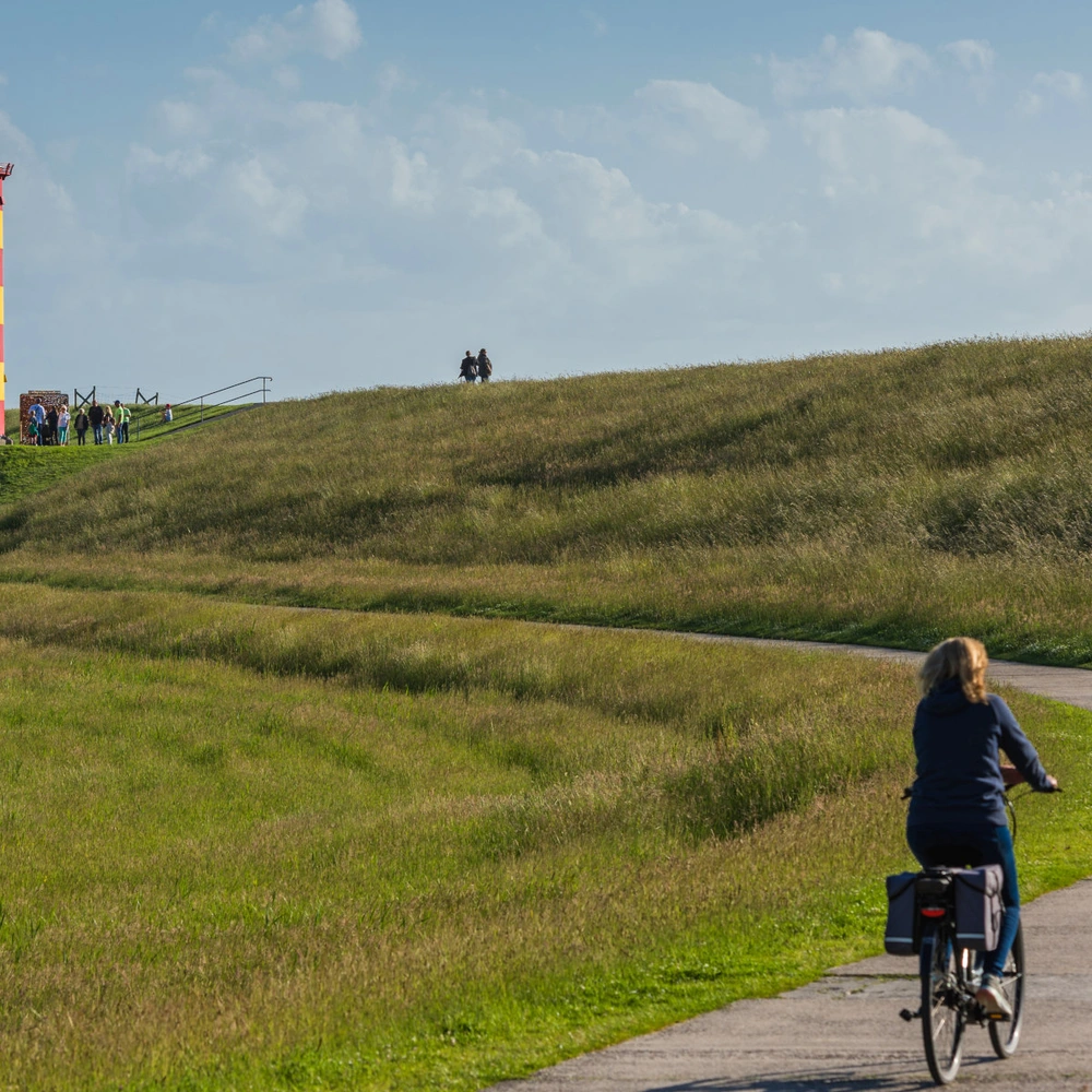 Frau fährt mit einem Fahrrad zum Pilsumer Leuchtturm in Ostfriesland